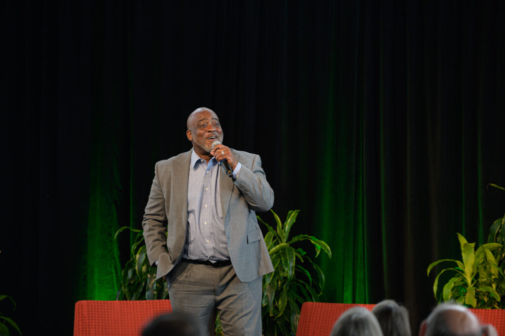 Desmond Meade, the keynote speaker at the Roots of Recovery event, stands on stage delivering his speech.